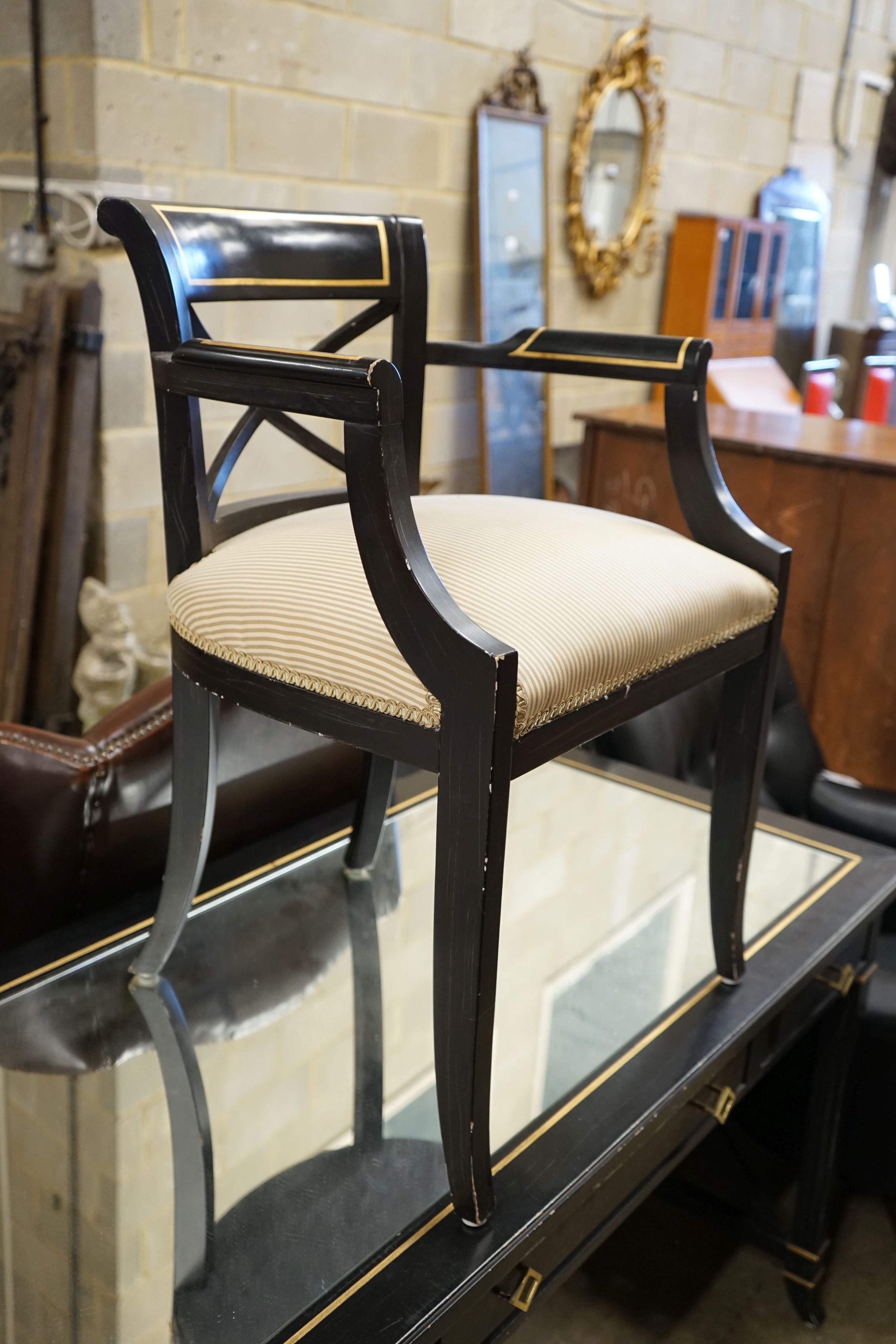 A painted mirrored three drawer ebonised writing table, length 140cm, depth 64cm, height 76cm together with a matching tub framed elbow chair